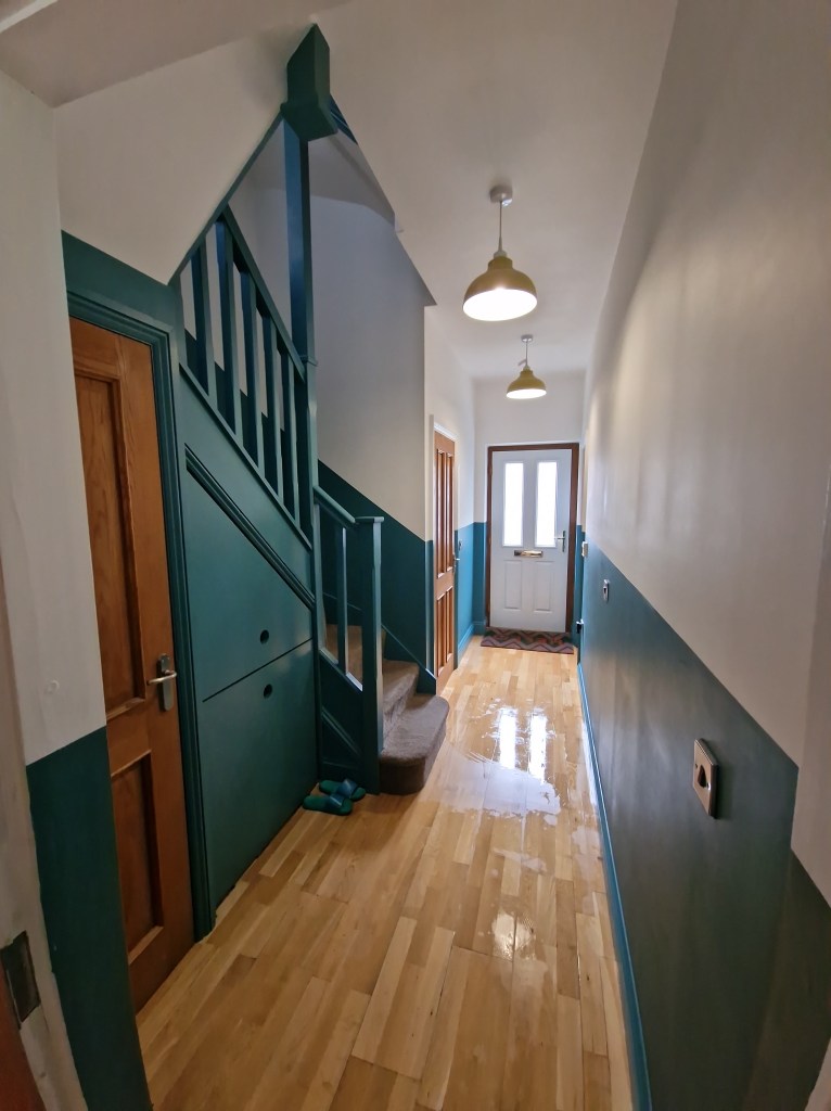 The image shows a brightly lit hallway with a staircase, featuring a door at the bottom and a second door at the top, addi...